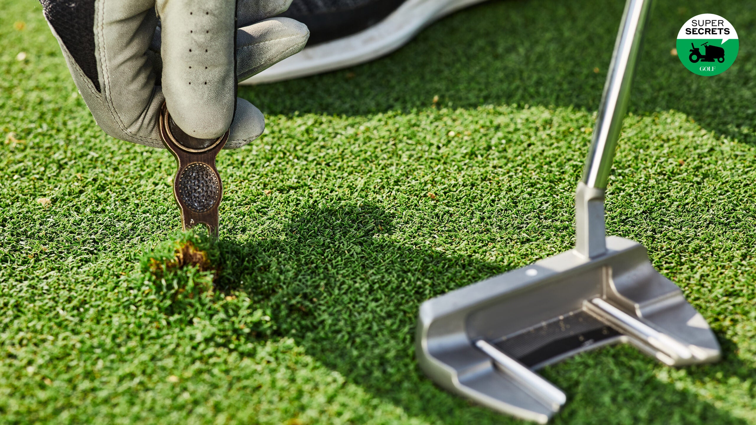 A golfer repairing a ball mark with a divot tool